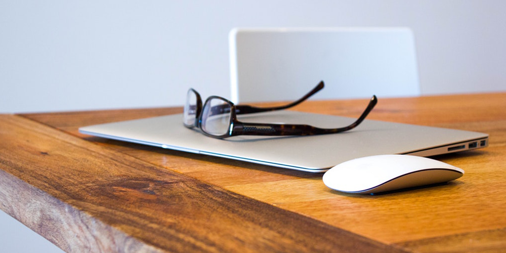 A laptop and glasses on a wooden table