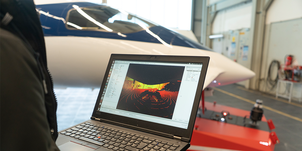 A person holding a laptop next to an aircraft
