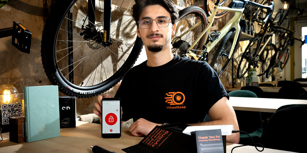 A man posing for a business photo, showing his bike security product